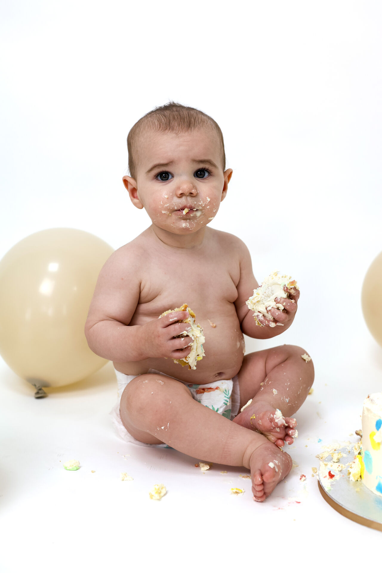 Baby smiling during a cake smash photoshoot with balloons