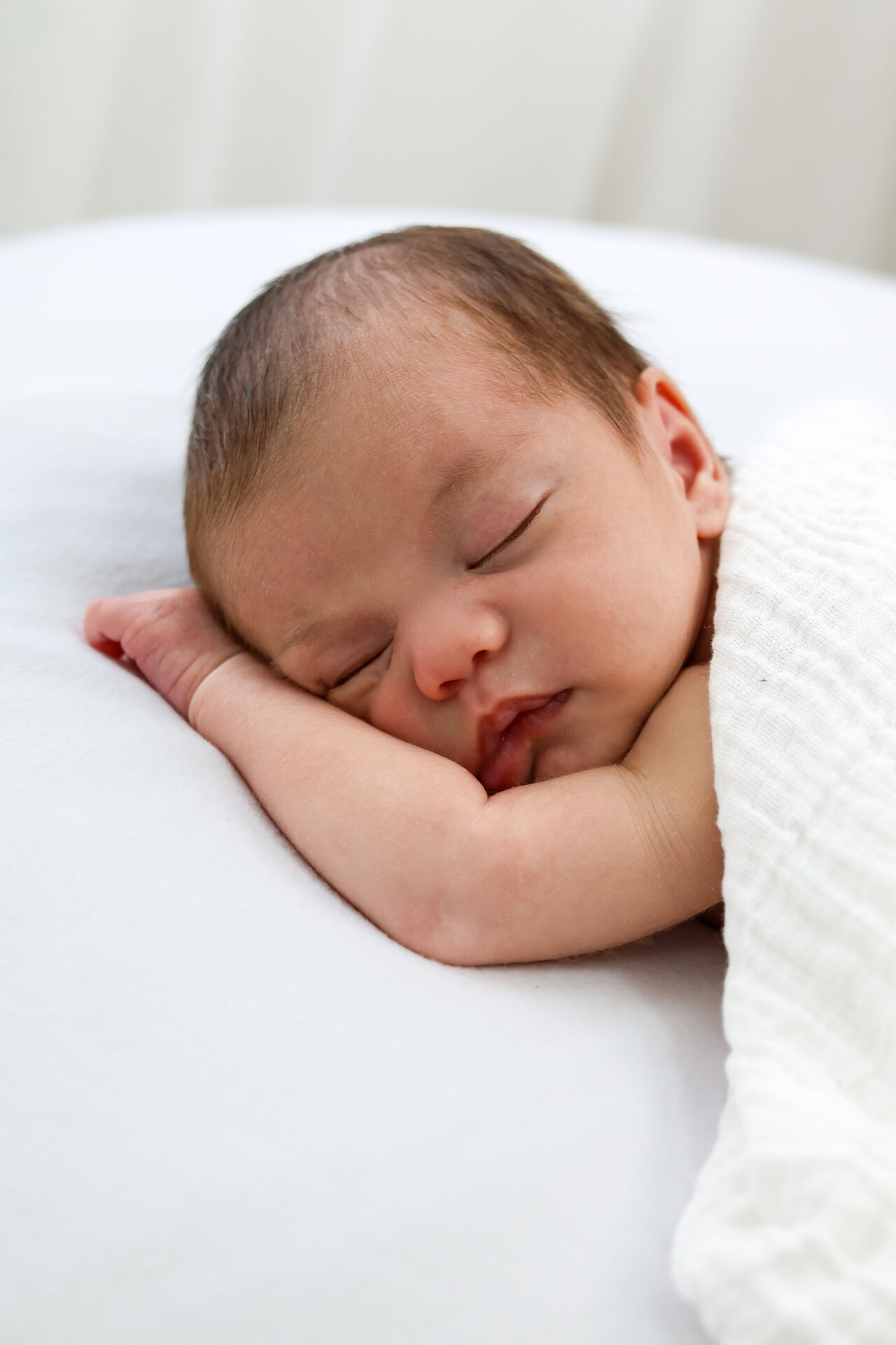 Newborn sleeping peacefully on parent's arm