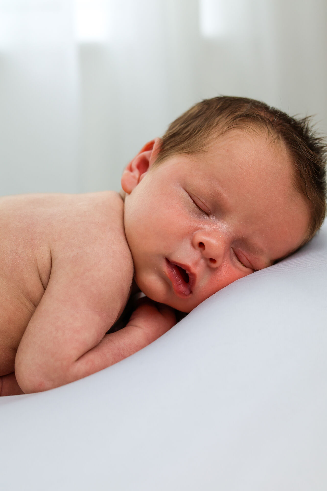 Newborn resting chin on hands during photoshoot